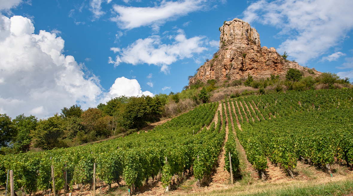 Natural rock formation above vineyard against blue skies